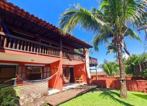 a house with a palm tree in front of it at Pousada Por do Sol in Ilhabela