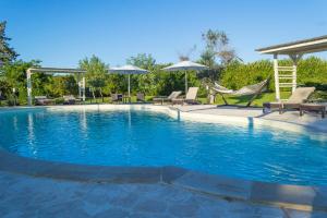 a large swimming pool with chairs and umbrellas at Masseria Un Posto al Sole in Otranto