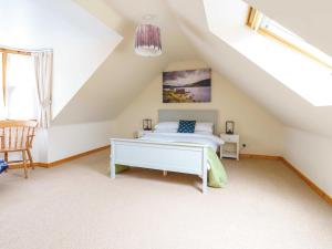 a attic bedroom with a bed and a chair at Milne's Brae, cosy, comfortable and centrally located in beautiful Braemar in Braemar
