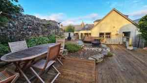 una casa y un patio con mesa y sillas de madera. en Milne's Brae, cosy, comfortable and centrally located in beautiful Braemar, en Braemar