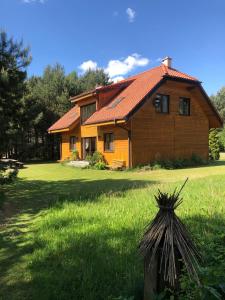 una casa de madera en un campo de césped verde en Za piecem en Guzowy Piec