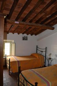 Cet appartement comprend une chambre avec deux lits et un plafond aux poutres apparentes. dans l'établissement Corte Prata, à Capannori
