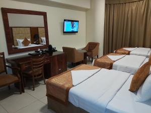 a hotel room with two beds and a desk and a mirror at Bliss Hotel in Dubai