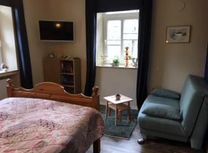 ein Schlafzimmer mit einem Bett und einem Stuhl und einem Fenster in der Unterkunft The Cozy Cottage in Rieden