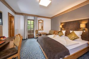 ein Hotelzimmer mit einem großen Bett und einem Schreibtisch in der Unterkunft Natur- & Auszeithotel Hüttenwirt in Hüttschlag