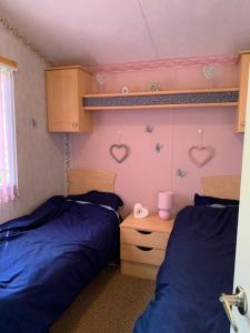 two beds in a room with hearts on the wall at Lower Hyde Caravan in Shanklin