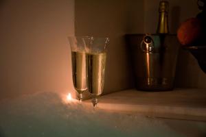 dos copas de champán sentadas en una mesa con una vela en Le Mura Luxury Room ROOM & PERSONAL SPA, en Castiglion Fiorentino