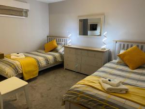 a bedroom with two beds and a dresser and a mirror at Ocean Hideaway @ Portmore Bay in Portstewart