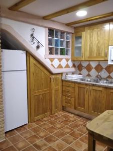 cocina con armarios de madera y nevera blanca en VENTA DE LA CASA NOGUERA en Riópar