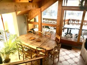 a wooden table and chairs in a room with a balcony at Chalet Rivière, 5 en-suite. in La Salle Les Alpes