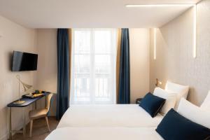 パリにあるオテル メルキュール パリ オペラ ラファイエットのベッド2台、デスク、窓が備わるホテルルームです。