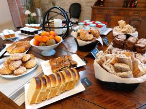 a table filled with different types of bread and pastries at Laiterie de Tocqueville B&B in Tocqueville