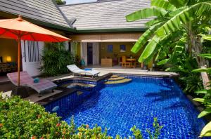 una piscina con sombrilla y un patio en Villa Topaz, en Laem Set Beach