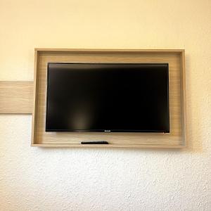 einen Flachbild-TV, der an einer Wand hängt in der Unterkunft Kyriad Direct Reims Bezannes in Reims