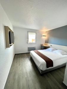 a hotel room with a bed and a television at Kyriad Direct Reims Bezannes in Reims