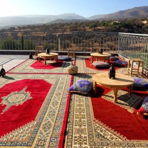 a patio with tables and carpets on a roof at VILLA AMALOU AVEC PISCINE FAMILLE UNIQUEMENt in Agadir