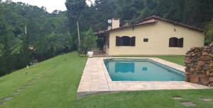 a house with a swimming pool in front of a yard at Chácara do Darcio SP in Itapecerica da Serra