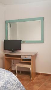 einen Schreibtisch mit einem TV und einem Spiegel an der Wand in der Unterkunft Casa Santa Maria I con barbacoa in Arévalo