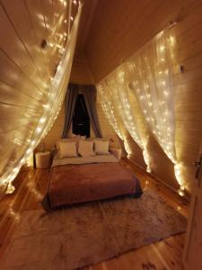 a bedroom with a bed in a tent with lights at Na Zakręcie - Domek Wiejski in Błędowo