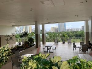 a large room with tables and chairs in a building at Your Little Piece of Paradise Pool, BBQ & Wifi at Inn on the Park 613 in Honolulu