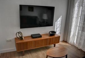 TV de pantalla plana en la pared con mesa de madera en Apartamentos Las Naranjas en Jerez de la Frontera