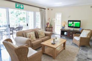 a living room with a couch and chairs and a tv at The Whitehouse Bed and Breakfast in Durban
