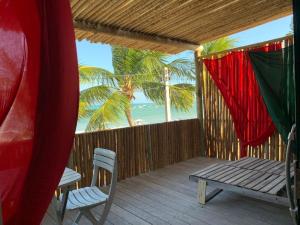 a porch with a table and a bench and the beach at Pousada Mama Pereira in Japaratinga