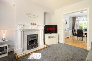 a living room with a fireplace and a dining room at Mulberry House - Luxurious and Modern 4-Bed in Solihull near NEC,JLR, Airport, Resorts World, HS2 in Solihull