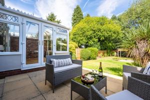a patio with chairs and a table with a bottle of wine at Mulberry House - Luxurious and Modern 4-Bed in Solihull near NEC,JLR, Airport, Resorts World, HS2 in Solihull