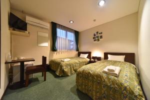 Habitación de hotel con 2 camas y escritorio en ホテルノマド日立, en Hitachi