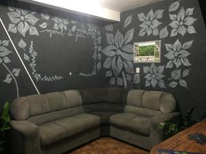 sala de estar con sofá y pared con flores en Camping e Pousada Primavera, en Lençóis