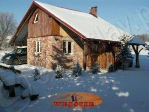 a snow covered house with a snowboard in front of it at Na Pograniczu domek w górach in Lasowka