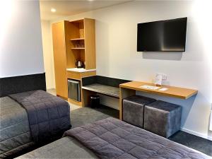 ein Hotelzimmer mit einem Bett, einem Schreibtisch und einem TV in der Unterkunft The Godley Hotel in Lake Tekapo