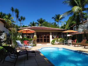 a house with a swimming pool with chairs and umbrellas at Pousada Cantinho do Sossego in Arraial d'Ajuda +70 photos