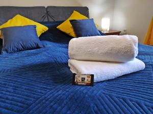 a blue bed with blue and yellow pillows and towels at Apartamentylove - Apartament Oliwia in Zakopane