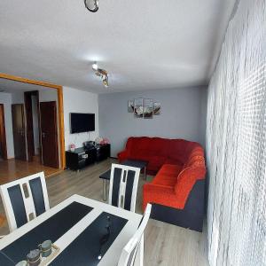 ein Wohnzimmer mit einem roten Sofa und einem Tisch in der Unterkunft Dovolenkový Dom Tatry in Vysoke Tatry - Tatranske Matliare