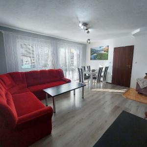 sala de estar con sofá rojo y mesa en Dovolenkový Dom Tatry, en Vysoke Tatry - Tatranske Matliare