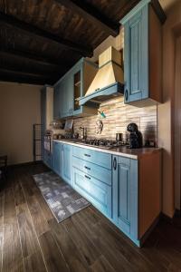 a kitchen with blue cabinets and wooden floors at L' Antica Trebbia - Rooms in Caltanissetta