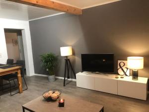 a living room with a flat screen tv and a table at Wesermarsch, Apartment mit zwei Schlafzimmern, Gästehaus, Stedinger Landhotel in Berne