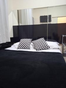 a bed with two black and white pillows on it at Hospedaria FOR755 in Fortaleza