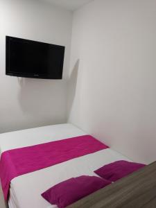 1 dormitorio con 1 cama y TV de pantalla plana en la pared en Apartaestudio Centro Comercial la Central, en Medellín