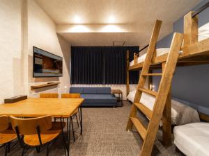 Cette chambre dispose d'une table à manger et de lits superposés. dans l'établissement WELLSTAY Namba, à Osaka