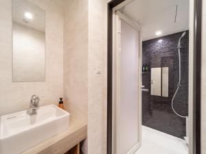 La salle de bains est pourvue d'un lavabo et d'une douche. dans l'établissement WELLSTAY Namba, à Osaka