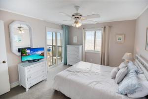una camera da letto bianca con un letto e una televisione di 2BR, 2Bath condo Oceanfront Getaway with pool a Myrtle Beach Altre 9 foto
