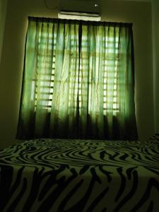 a bedroom with a bed with a green curtain at Alma Homestay 
