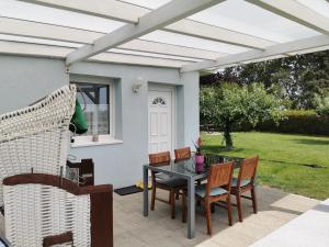 Bungalow 4 Pers. في Elmenhorst: فناء بطاولة وكراسي تحت بروغولا بيضاء