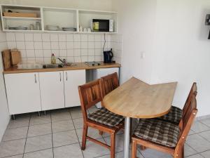 Bungalow 4 Pers. في Elmenhorst: مطبخ مع طاولة خشبية وكرسيين
