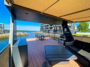 einen Balkon mit Sofa und Tisch und Blick auf das Wasser in der Unterkunft MarinaVilla in Nykøbing Falster