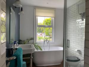 a bathroom with a white tub and a window at Boutique City Centre Home in Chichester