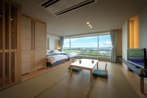 a hotel room with a bedroom and a bed and a table at Hotel Matsushima Taikanso in Matsushima